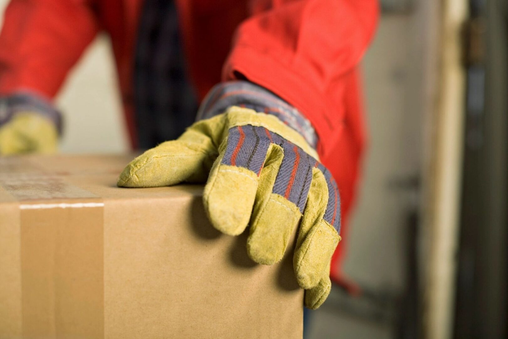 A person wearing gloves and holding onto boxes.